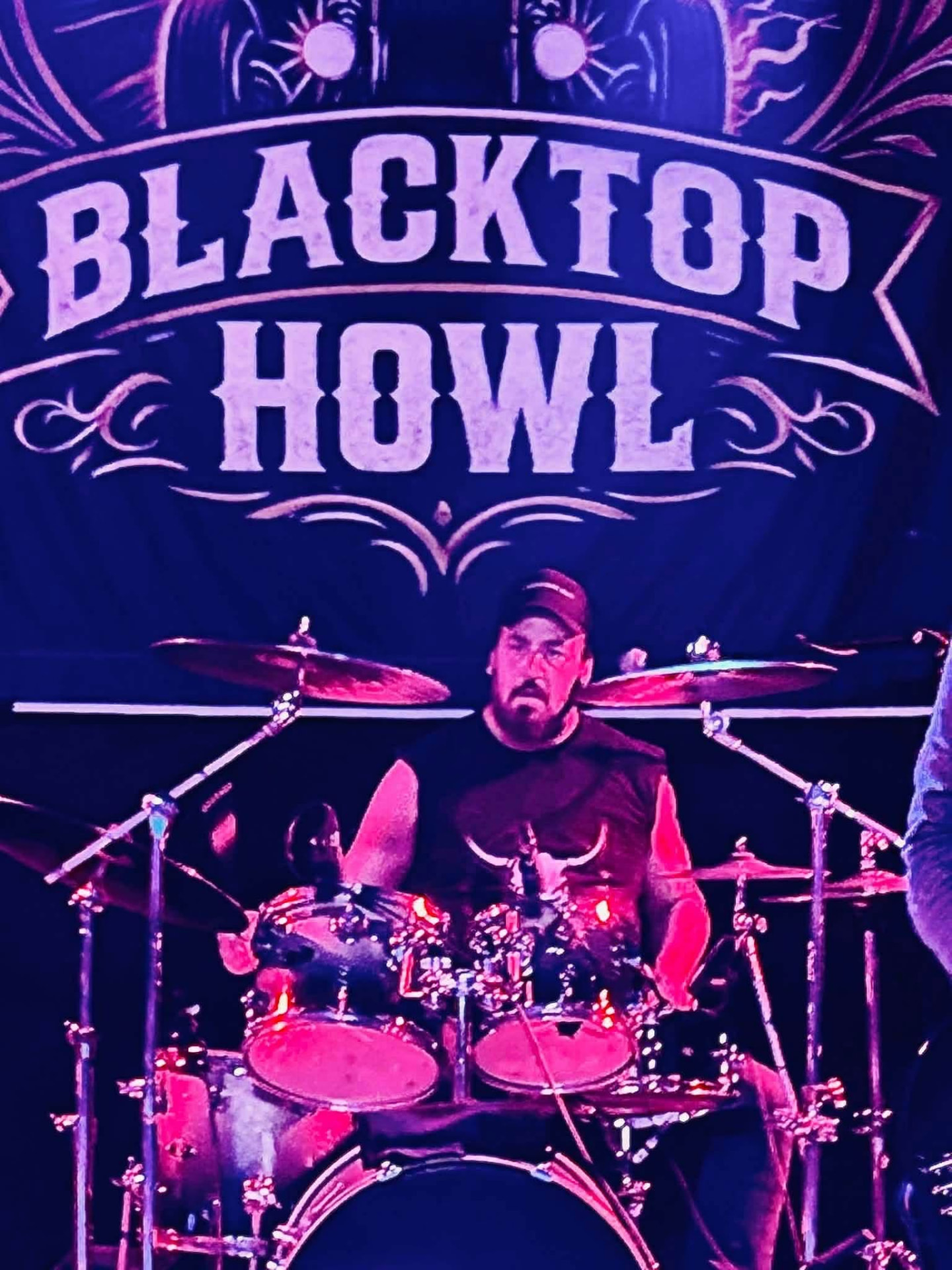 Blacktop Howl drummer in front of the band backdrop