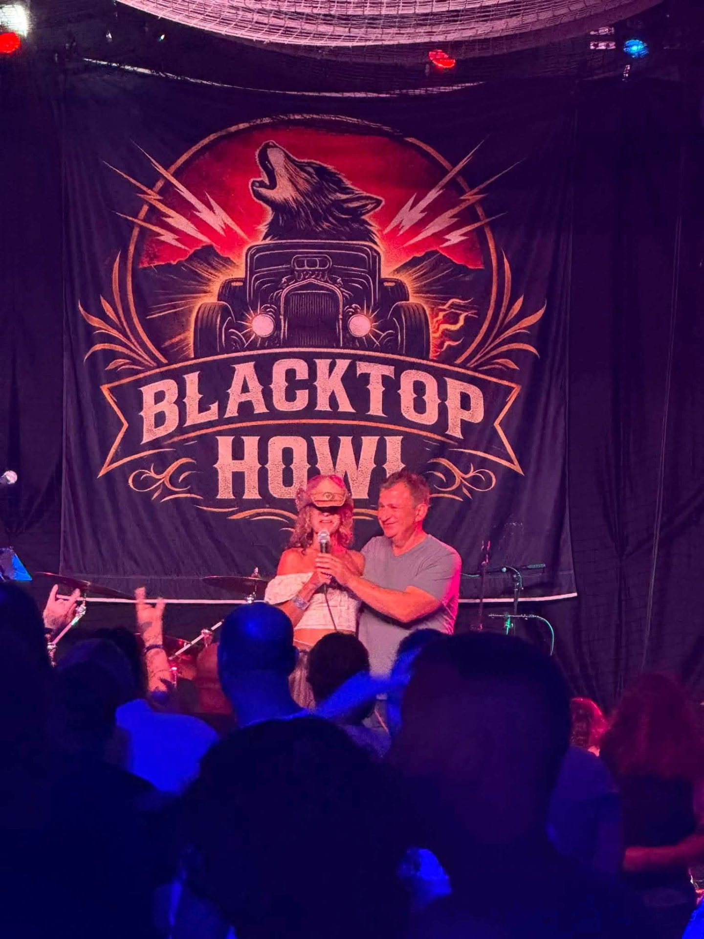 Blacktop Howl banner behind the stage with a fan singing along