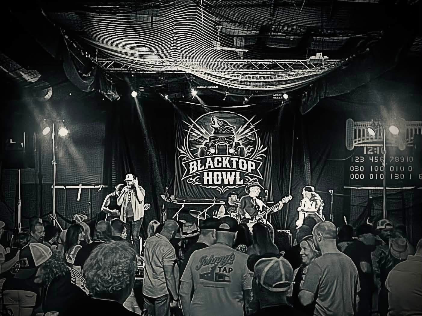 Wide black and white shot of a Blacktop Howl show and the crowd