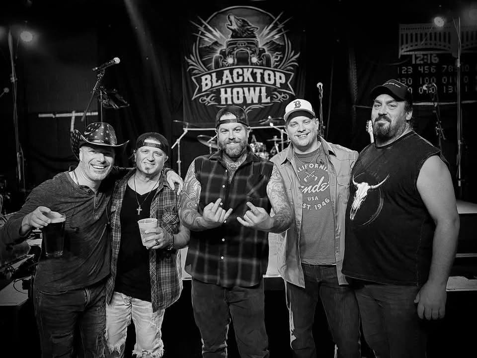 Black and white group photo of Blacktop Howl on stage