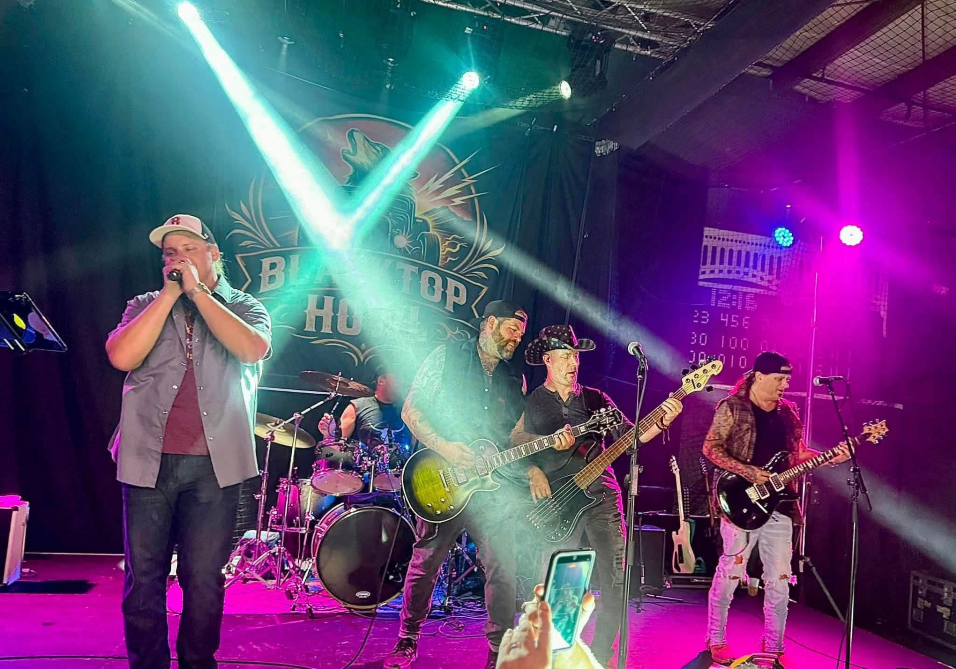 Blacktop Howl full band performing under pink and teal stage lights